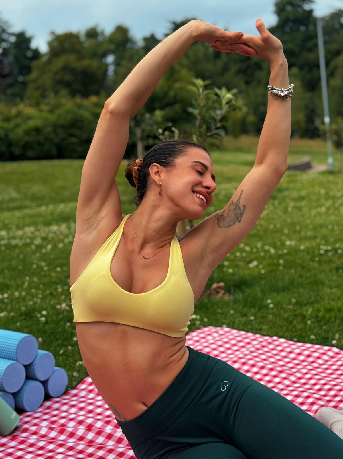 Beca doing a side stretch with arms overhead