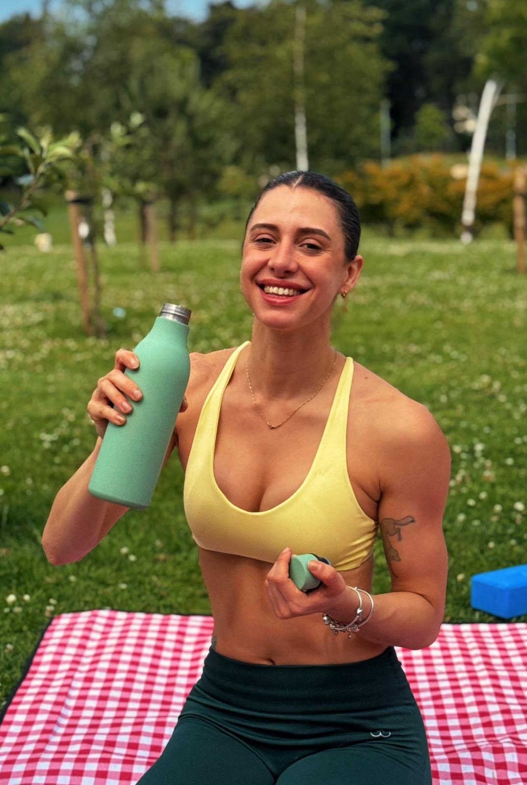 Beca smiling with a green water bottle on a picnic blanket